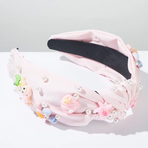 Détail d'un serre-tête en tissu rose avec perles, coquillages en résine et étoiles de mer