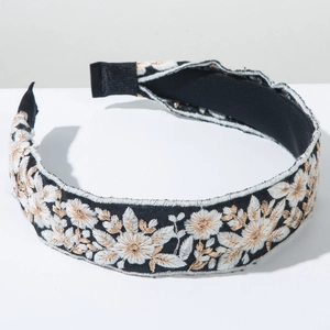 Detailed embroidery on bohemian headband featuring white and gold floral stitch patterns
