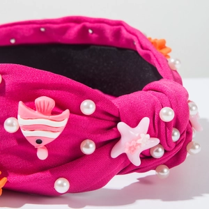 Vue macro détaillée du serre-tête magenta avec perles et décorations d'étoiles de mer