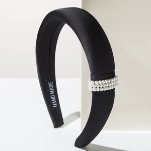 Detailed close-up of a handmade black fabric headband decorated with three rows of white pearls
