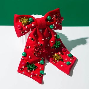 Rote Weihnachts-Haarschleife mit bunten Perlen und Metallsternen auf grünem Grund