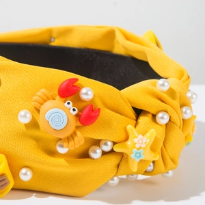 Détail du serre-tête en tissu jaune avec perles, crabe 3D et accessoires marins étoiles