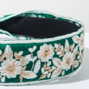 Detailed close-up of floral embroidery on a green bohemian headband with satin finish