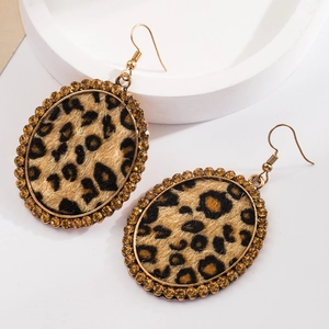 Close-up of leopard print oval earrings with amber rhinestones and gold metal hooks