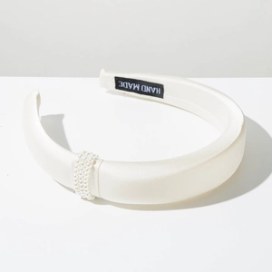 Detail of cream satin padded headband with imitation pearl accents and handmade label