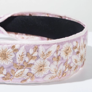 Detail of pink fabric headband featuring intricate white and gold floral embroidery crafts
