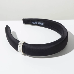 Detailed macro view of black satin pearl headband with HAND MADE label on inner lining