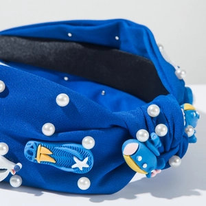 Détail d'un serre-tête en tissu bleu avec perles blanches et pendentifs de dessin animé
