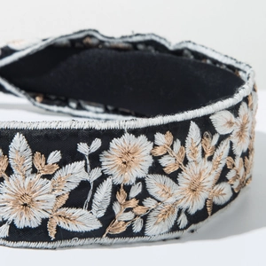 Close-up of bohemian headband featuring white and champagne gold floral embroidery details