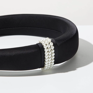 Detailed close-up of a black satin padded headband with triple rows of white pearls