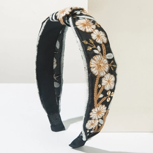 Detail of hand-embroidered floral patterns and gold sequins on black knotted headband