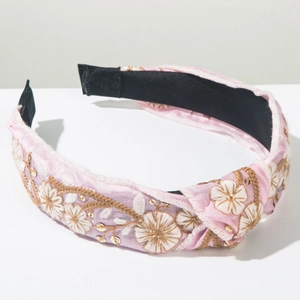 Close-up of pink satin headband featuring white floral embroidery and golden sequins