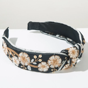Detailed close-up of handmade floral embroidery and gold sequins on a black knotted headband