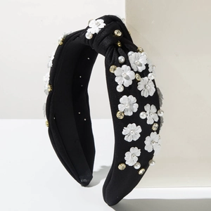 Detail of black fabric knotted headband featuring white flowers, pearls and rhinestones