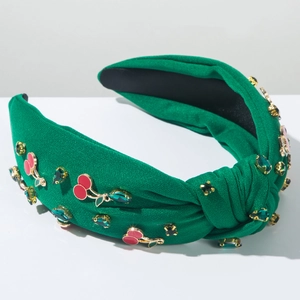 Détail d'un serre-tête tricoté vert avec des ornements cerise et des pierres précieuses