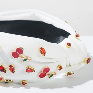 Gros plan du serre-tête noué blanc avec cerises en cristal rouge et détails métalliques