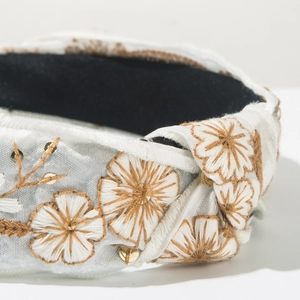 Detail of hand-embroidered floral patterns on light blue-grey satin knotted headband