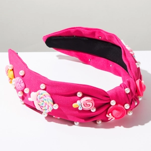 Dettaglio del cerchietto in tessuto rosa con lecca-lecca colorati, perle e rose
