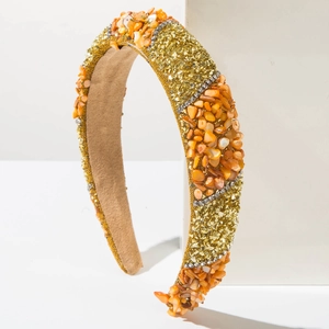 Fashionable wide headband with orange shell fragments and gold bead accents on white stand