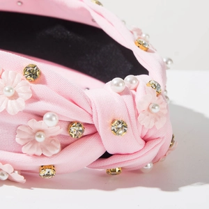 Close-up of pink fabric headband featuring floral ornaments, pearls and crystal rhinestones