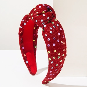 Detail view of the red knotted headband showing multi-color sequins and festive fabric texture