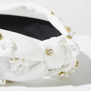 Detail of white fabric headband with delicate pearls, crystals and floral embroidery