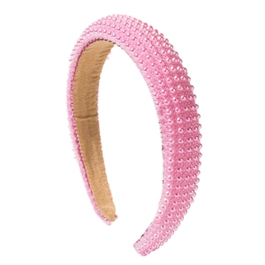 Pink padded headband with faux pearls and brown velvet lining on a white background
