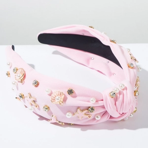 Detail van roze geknoopte haarband met parels, strass en gouden zeester bedeltjes