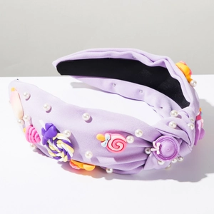 Dettaglio del cerchietto in tessuto viola con ciondoli a caramella e decorazione di perle