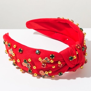 Détail d'un serre-tête de Noël rouge avec nœud, motifs renne et perles dorées brillantes