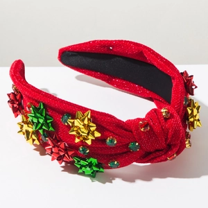 Détail du serre-tête rouge pailleté avec nœuds étoiles festifs et strass colorés