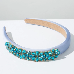 Detailaufnahme des hellblauen gepolsterten Satin-Haarreifs mit funkelndem Strass-Blumenmuster
