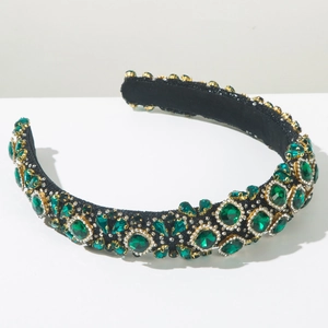 Detailed close-up of emerald green rhinestones and crystals on a baroque headband