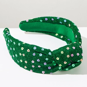 Close-up of green knotted headband with colorful sequins and snowflake patterns for Christmas