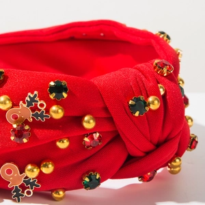 Détail du serre-tête de Noël rouge avec perles dorées, strass et pendentif en forme d'élan