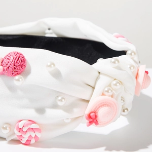 Dettaglio del cerchietto annodato bianco con ciondoli rosa a forma di caramella