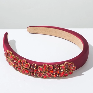 Detail eines roten gepolsterten Haarreifs mit barockem Strassblumenmuster in Goldfassung