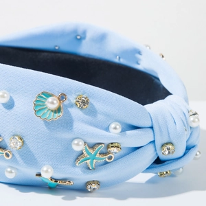 Detail van een lichtblauwe haarband met zeethema met zeesterren, schelpen en parels decor