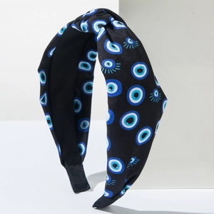 Detail of black evil eye print headband featuring a wide knotted fabric design and non-slip lining
