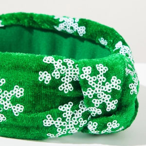 Detailed view of green velvet knotted headband with white sequin snowflake patterns