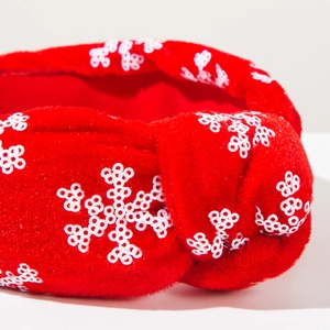 Detailed macro view of festive red velvet headband with white sequin snowflake patterns