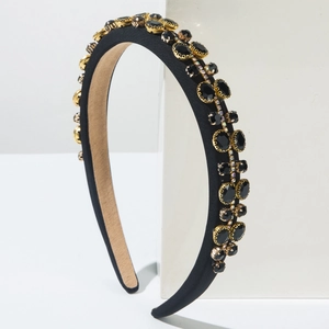 Detailed side view of black padded headband with embedded dark crystals in gold settings