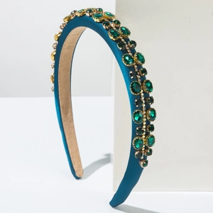 Detailed shot of dark blue satin headband with inlaid green gems and gold settings