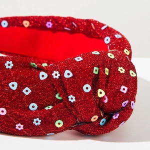 Detailed view of red glitter knotted headband with colorful sequin floral ornaments