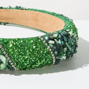 Close-up of emerald green headband with rhinestones and crushed crystal textures