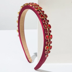 Detail of red satin headband with rows of ruby-like crystals in gold claw settings