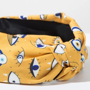 Detail of yellow fabric headband with blue evil eye prints and stylish knotted design