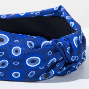 Detail of blue fabric headband with evil eye pattern and elegant knotted design