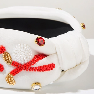 Detail of hand-sewn beads and rhinestones on a white knotted fabric headband