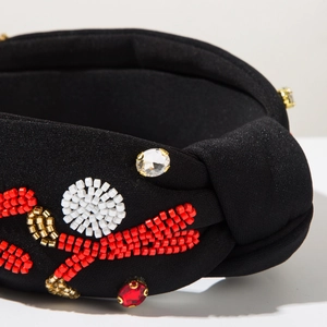 Detail of handmade beadwork with rhinestones and knot design on black fabric headband